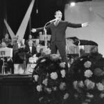 Charles Aznavour chantant sur scène devant un orchestre, aux Pays-Bas dans les années 1960