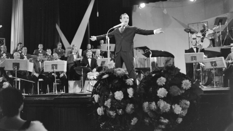 Charles Aznavour chantant sur scène devant un orchestre, aux Pays-Bas dans les années 1960